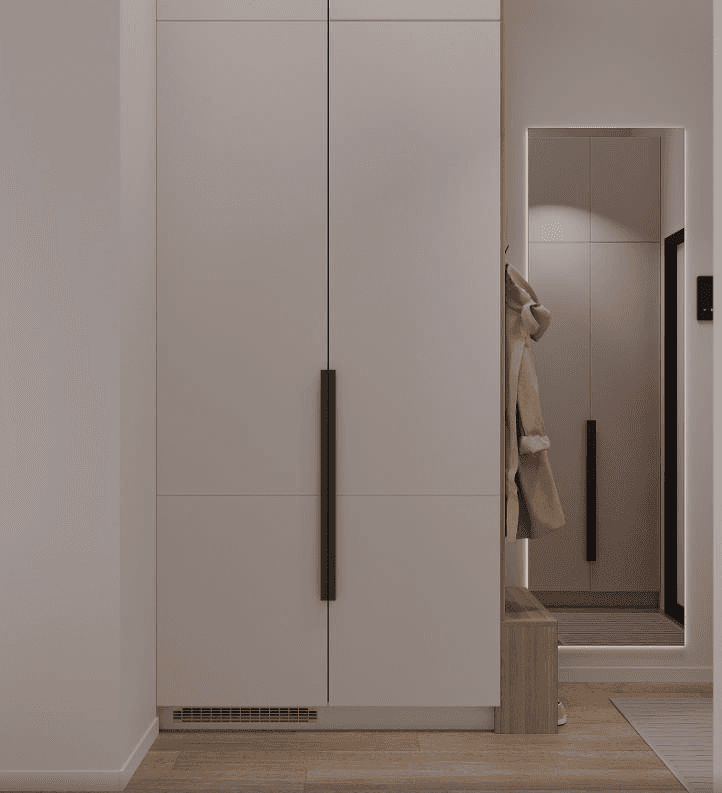 A light-coloured tall cupboard with long black handles and a full-height mirror beside it.