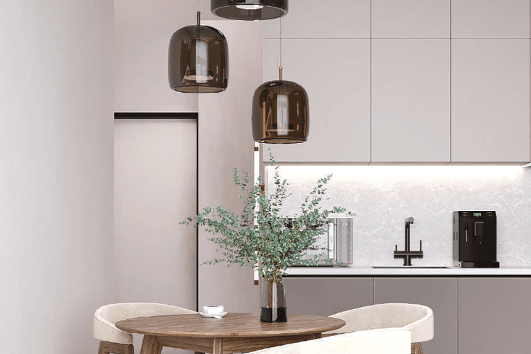 White kitchen cabinets, a black tap, a round wooden dining table and pendant lights.