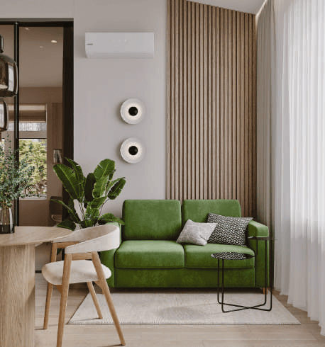 A green sofa, vertical wooden wall slats, a sheer curtain and a wall-mounted air conditioner.
